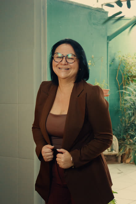 Ketlyn de blazer, sorrindo na entrada do escritório