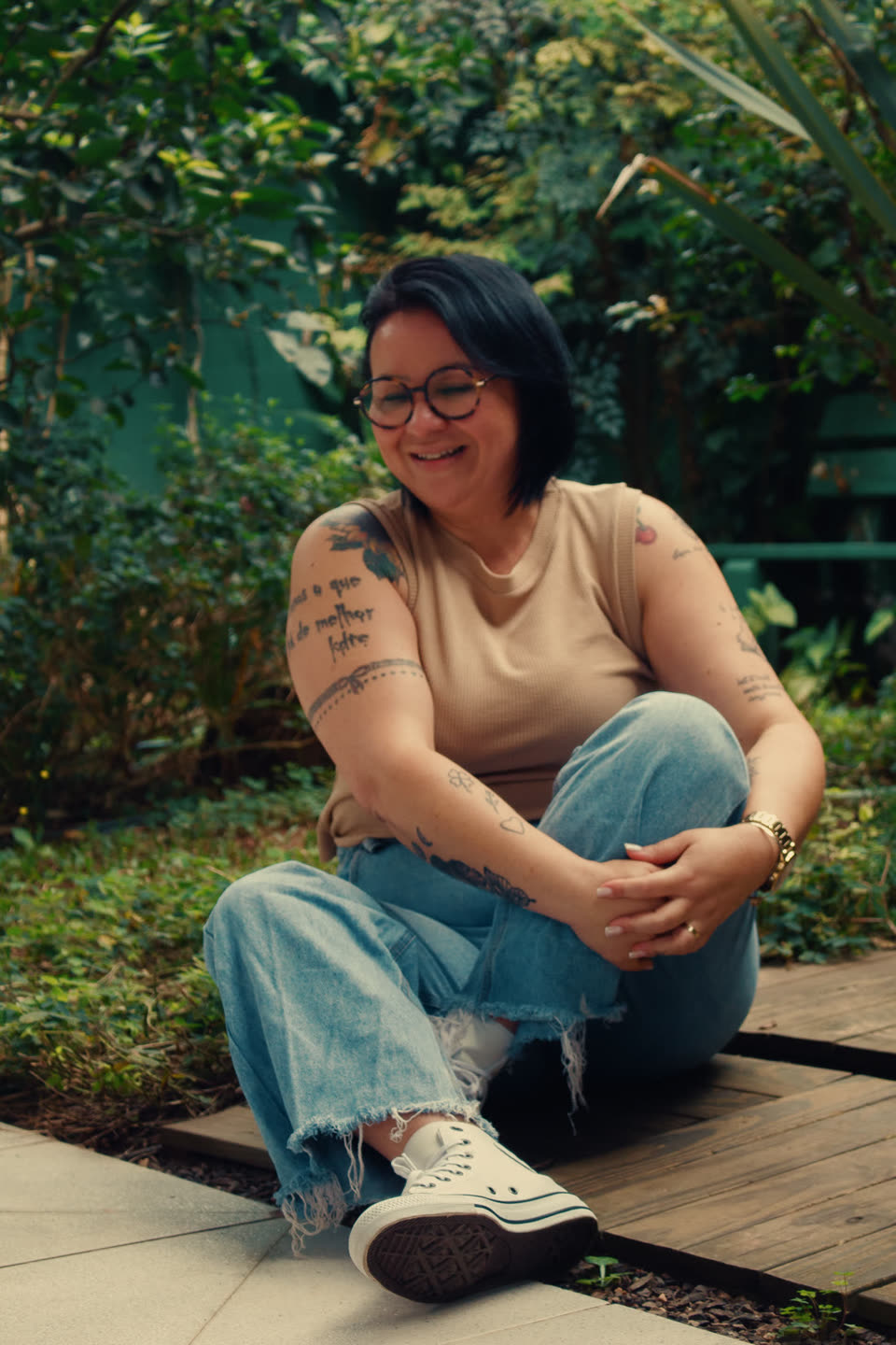 Ketlyn sentada no jardim, em roupa casual